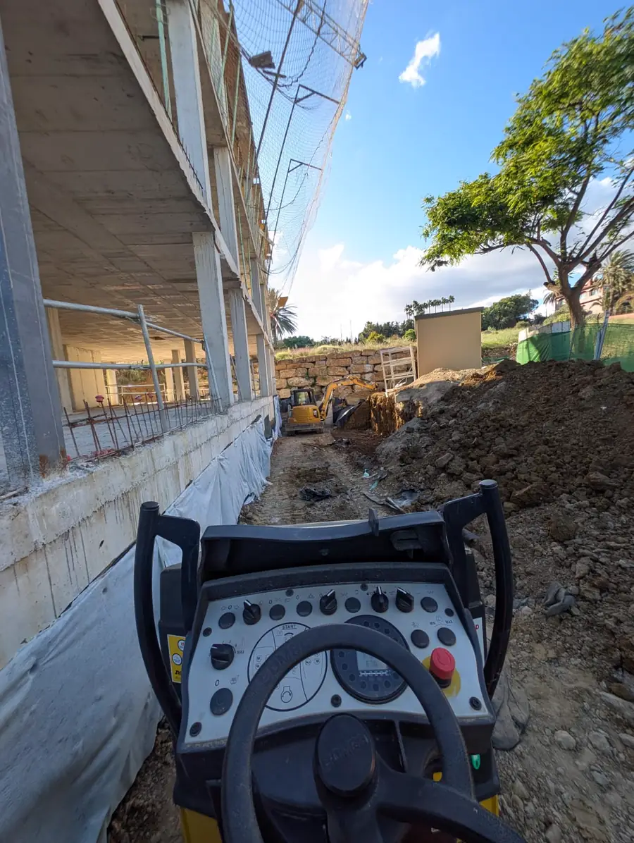 Rodillo compactador trabajando junto a una vivienda en construcción